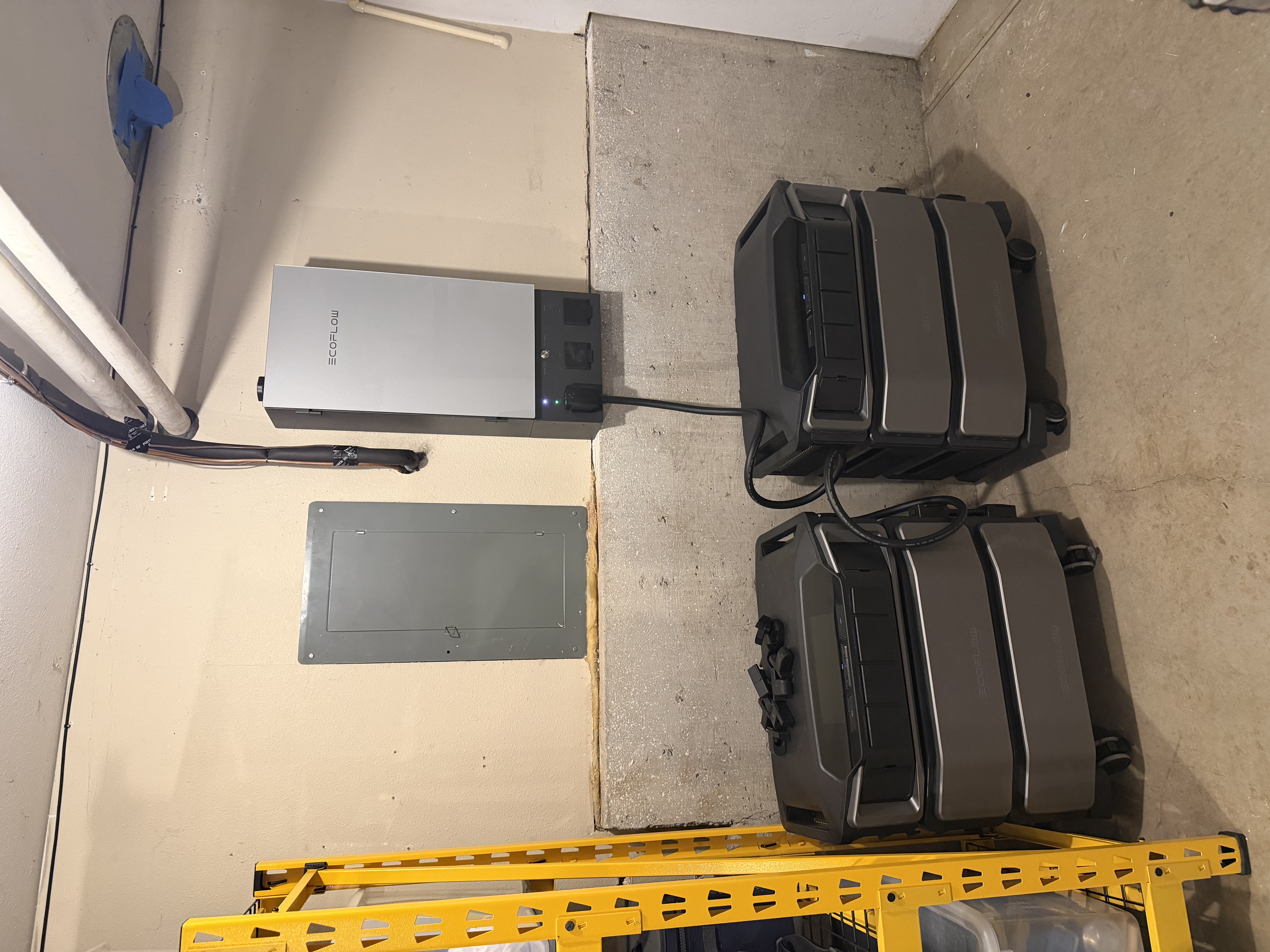 The original Panel-1 install: an EcoFlow Smart Home Panel 2 mounted on the basement wall, with two Delta Pro Ultra battery units stacked on the floor next to it.
