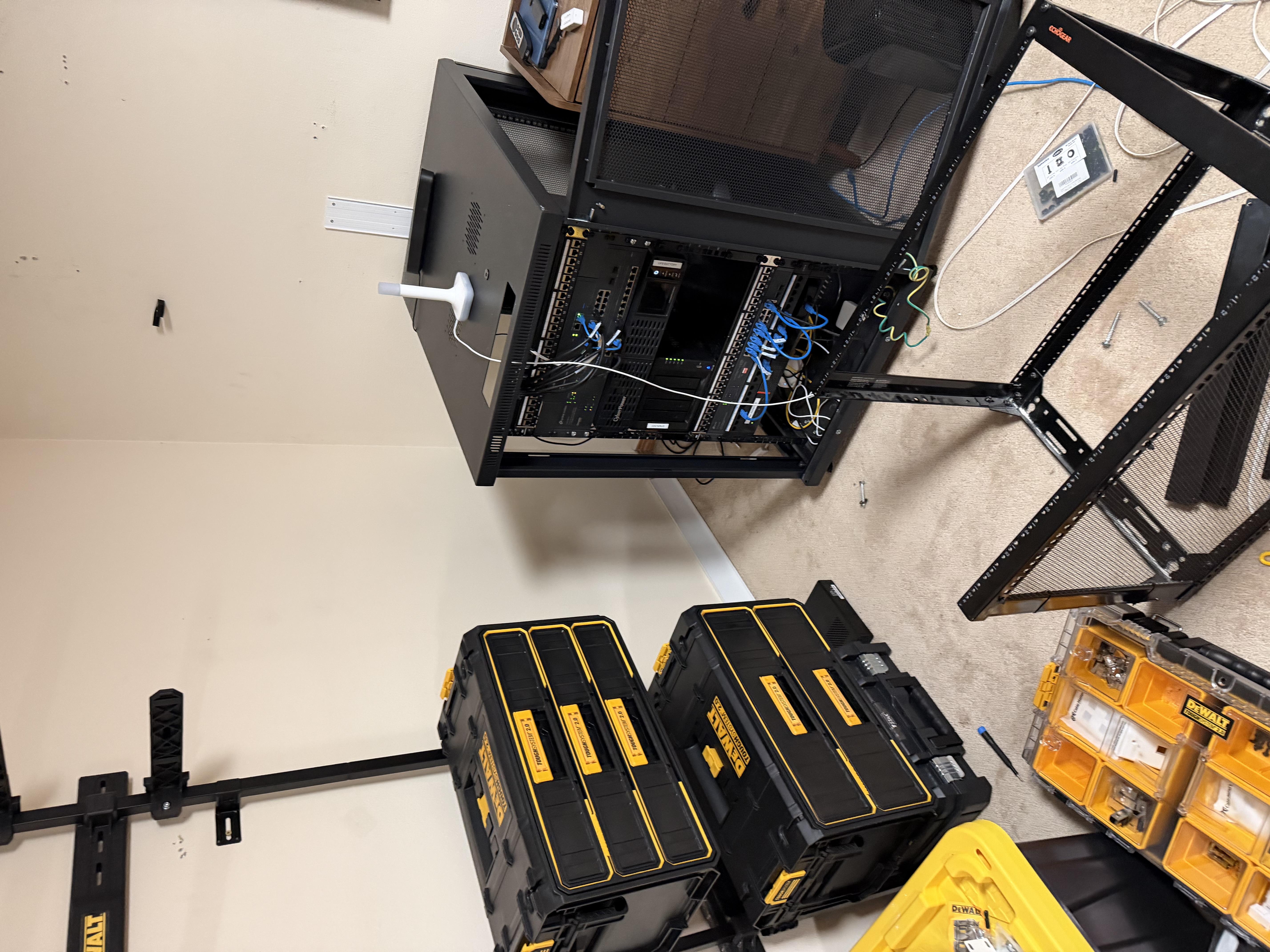 The new Startech rack standing in the gym next to my older open rack, with stacks of DeWalt tool boxes nearby. Work in progress, nothing wired up yet.